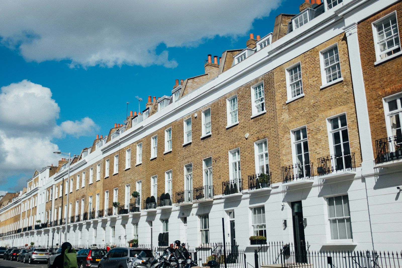 A row of London terraced houses under a blue sky